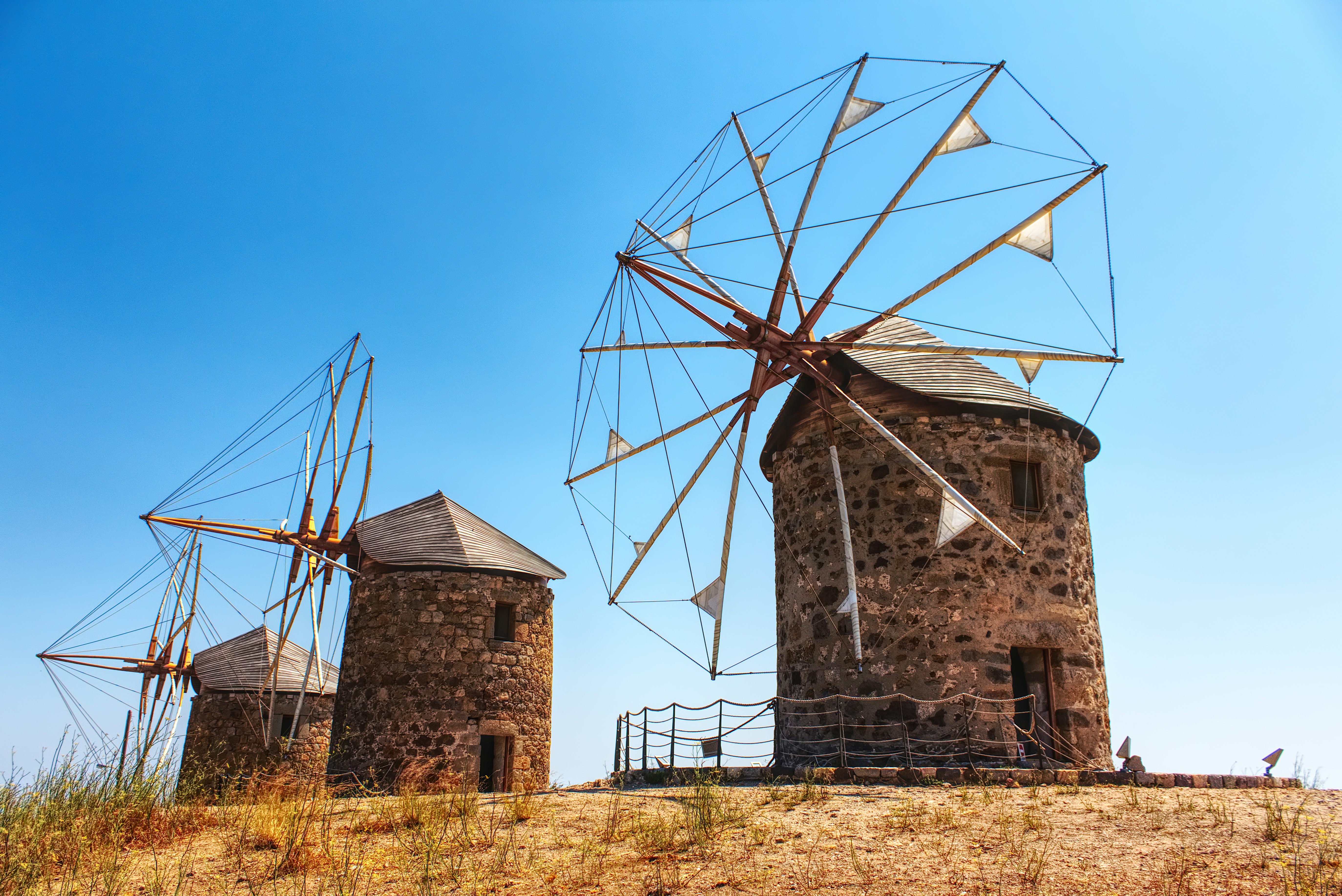 three brown windmills on hill